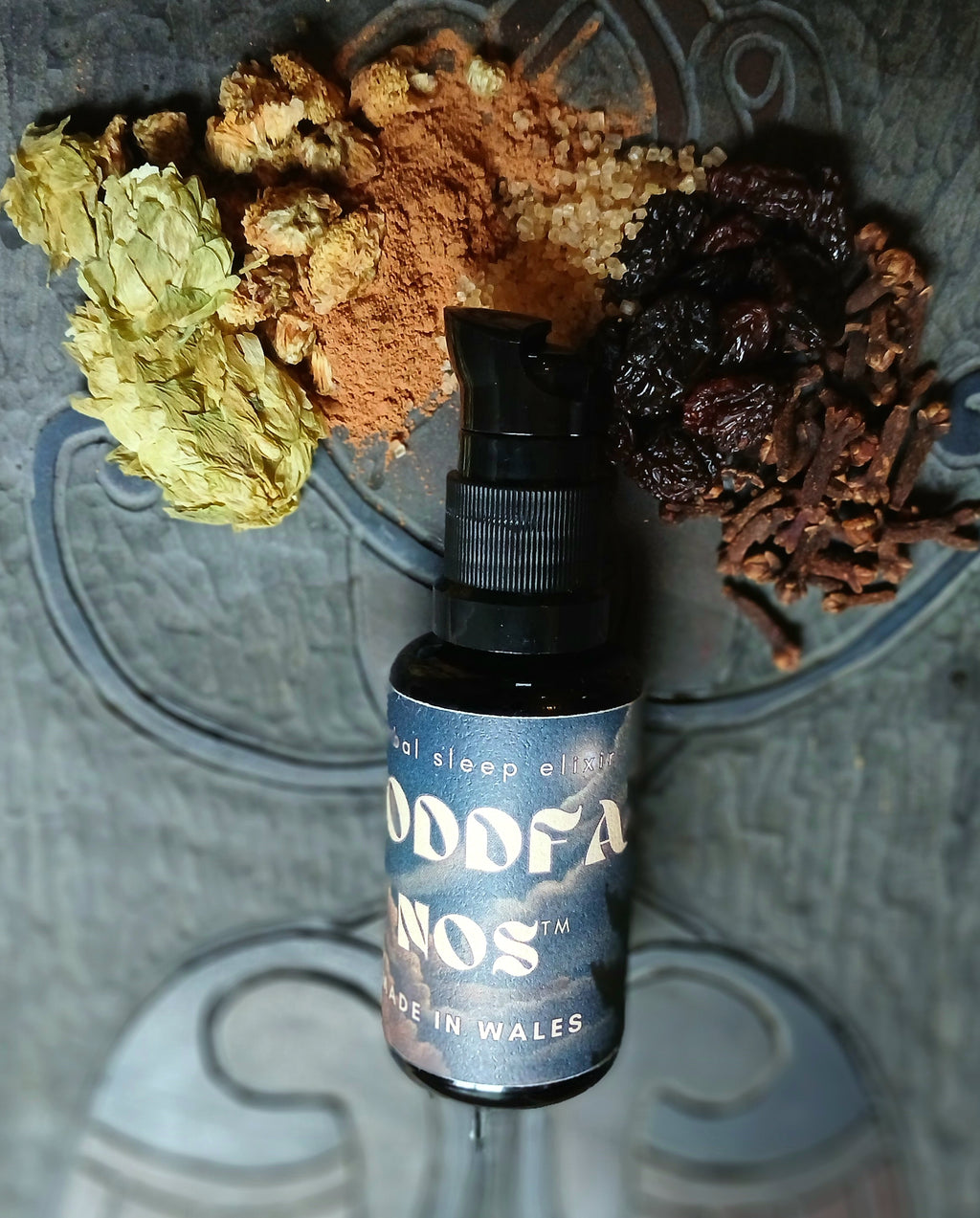Bottle of 'Nodffa Nos product with dried herbs and spices on a slate surface