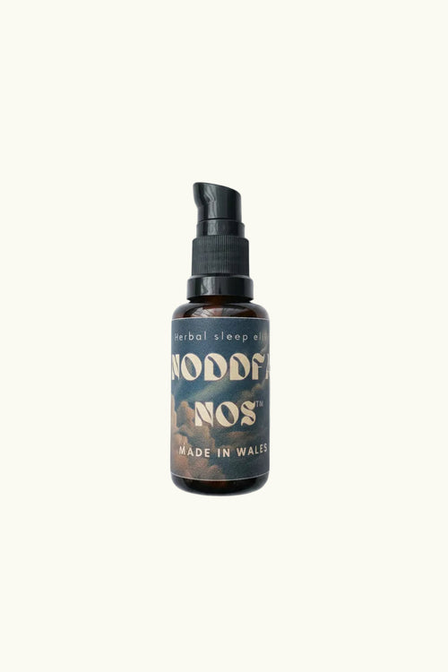 A small amber glass pump bottle with a black pump dispenser and a dark label reading 'noddfa nos' and 'MADE IN WALES', centered on a plain light background.